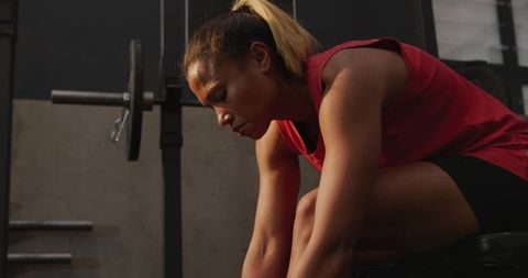 Focused Woman Preparing for Workout Tying Shoes in Gym