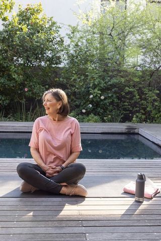 Senior Woman Enjoying Outdoor Yoga by Poolside in Morning Sun