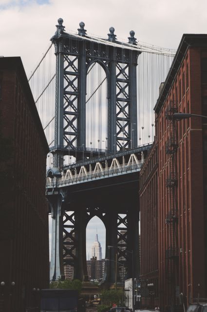 Urban scenery showing the Manhattan Bridge with the Empire State Building visible through the bridge structure. Ideal for use in travel promotions, architectural studies, urban development projects, and presentations on New York City's landmarks and attractions.