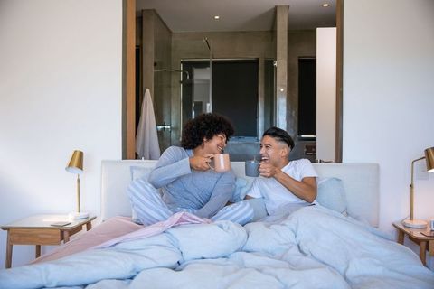 Friends in Pajamas Enjoying Coffee on Bed with Laughter