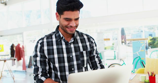 Smiling Man in Checkered Shirt Working on Laptop in Bright Office - Download Free Stock Images Pikwizard.com