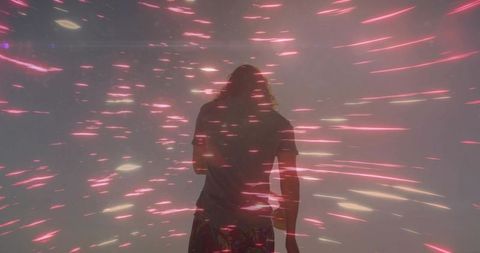 Standing silhouette facing neon pink light trails in hazy studio atmosphere