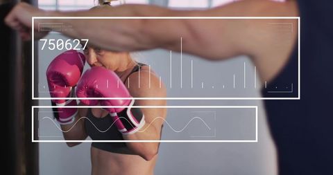 Woman boxing with bright pink gloves and digital fitness hud overlay, trainer coaching
