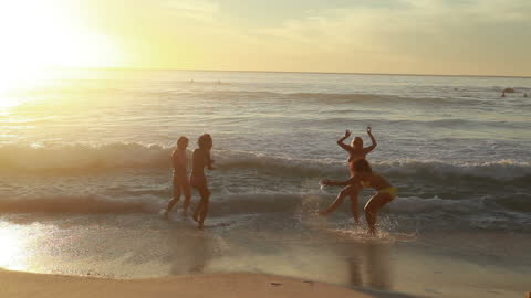 Girls Enjoying Sunset on the Beach with Playful Waves