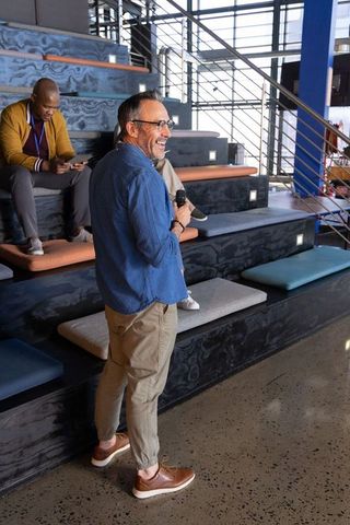 Midlife presenter leading casual workshop in modern industrial office with tiered seating