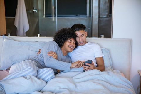 Couple Relaxing In Modern Bedroom Using Smartphone