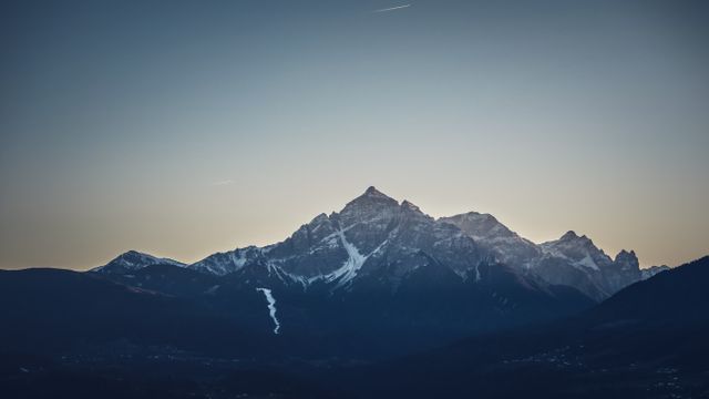 Snow-capped mountain range glowing under evening sky. Ideal for travel blogs, nature magazines, environmental projects, wallpaper, meditation and relaxation themes, posters promoting outdoor activities.