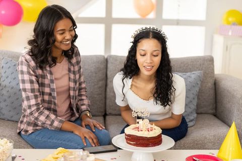 Friends celebrating 18th birthday with red velvet cake on cozy gray couch