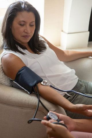 Hispanic Woman in Home Care Setting Receiving Blood Pressure Check