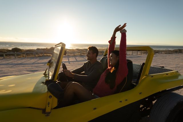 Couple enjoying a scenic drive in a beach buggy along the coast at sunset. Perfect for travel blogs, romantic getaway promotions, and summer adventure advertisements.