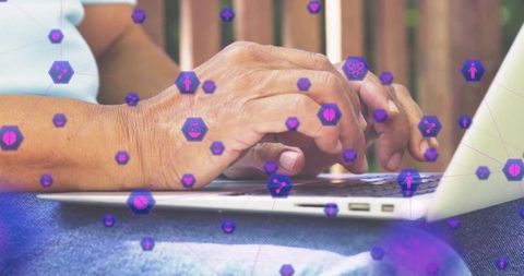 Senior adult using laptop outdoors with digital icons