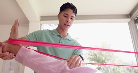 Physiotherapist Guiding Senior with Resistance Band Exercises