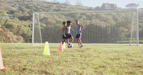 Boys Practicing Soccer Drills in Field with Ball and Cones