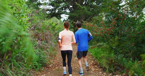 Mother and son jogging on lush forest trail, promoting health and bonding