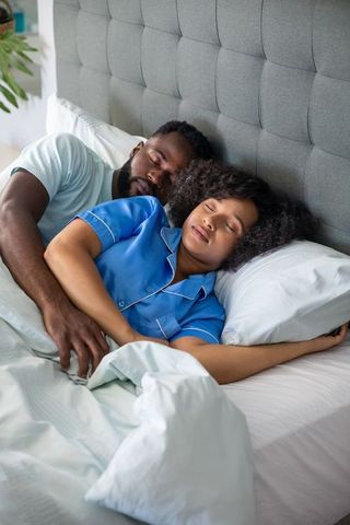 Interracial Couple Embracing Peaceful Sleep in Cozy Bedroom