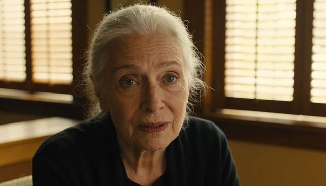 Thoughtful senior woman with gray hair in dark cardigan speaking in intimate wood booth