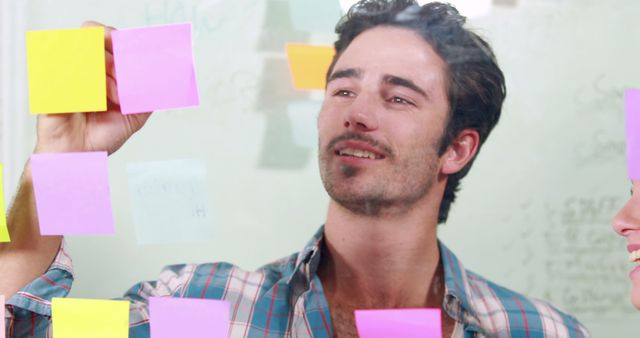 Young Man Writing Ideas on Sticky Notes During Team Brainstorming Session - Download Free Stock Images Pikwizard.com