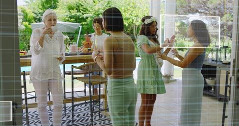 Bridal shower gathering celebrating poolside with pastel dresses, floral crown and sash