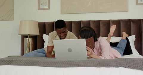 Couple Planning Honeymoon with Laptop and Passport on Cozy Bed