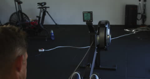 Man Practicing Rowing on Machine in Gym