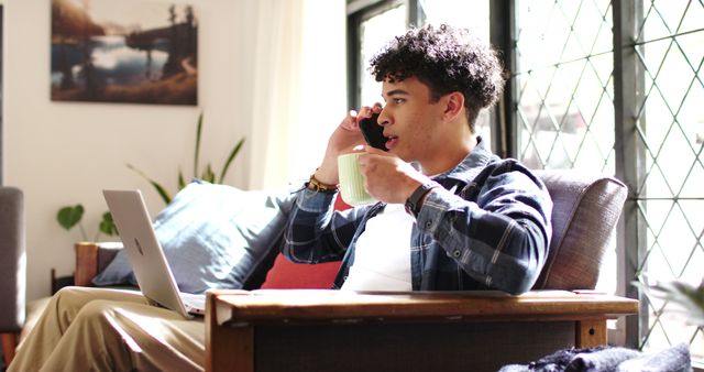 Young Man Taking a Phone Call While Working on Laptop at Home - Download Free Stock Images Pikwizard.com