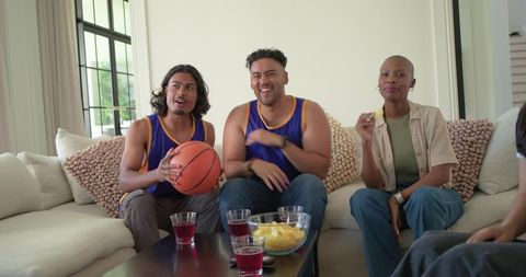 African american friends cheering during basketball game at home in blue gold jerseys