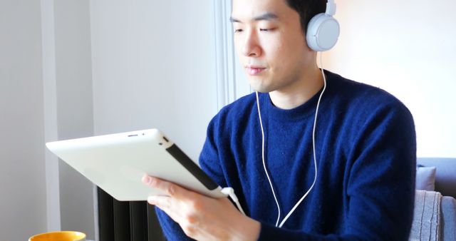 Man Wearing Headphones Using Digital Tablet at Home - Download Free Stock Images Pikwizard.com