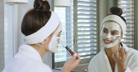 Woman Applying Creamy Facial Mask with Soft Brush
