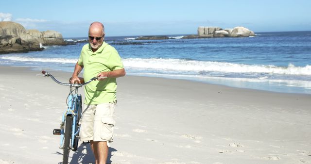Elderly man walking on sandy beach with a bicycle on a sunny day. Beautiful ocean view in the background. Perfect for advertising vacation packages, retirement living, wellness, and outdoor recreational activities.
