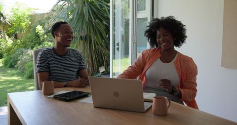 Happy couple discussing future plans with laptop at home