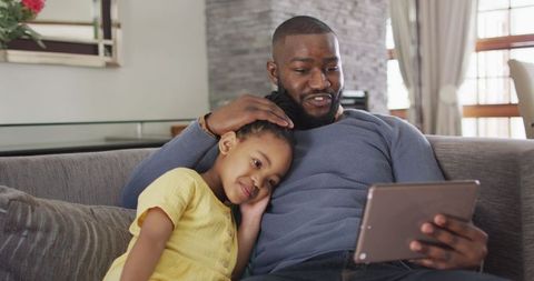 Father and Daughter Bonding with Tablet on Home Sofa