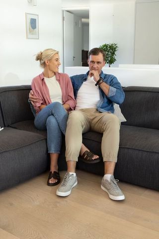 Couple cuddling on modern dark gray sectional sofa in bright minimalist living room