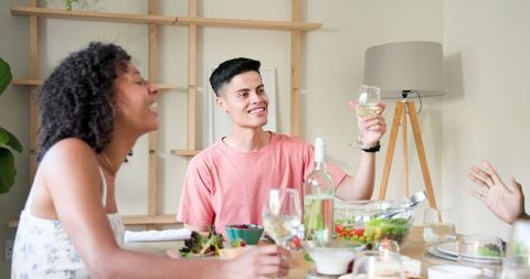 Friends Celebrating with Laughter Over Dinner at Cozy Home