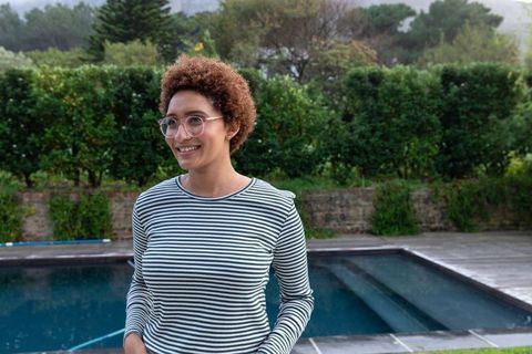 Smiling woman in striped shirt by pool in nature setting