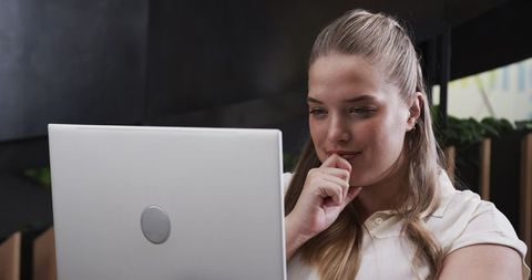 Concentrated Woman Working on Laptop in Modern Office Environment