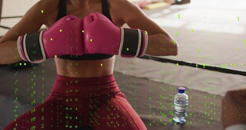Female boxer kneeling wearing pink gloves and gear in ring with digital data overlay