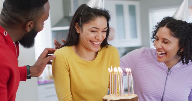 Happy biracial woman holding birthday cake celebrating birthday with diverse friends, in slow motion. Celebration, birthday, friendship and tradition concept.