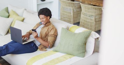 African American Man Shopping Online with Laptop on Sofa