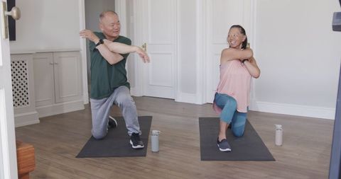 Senior couple enjoying home workout stretching on yoga mats