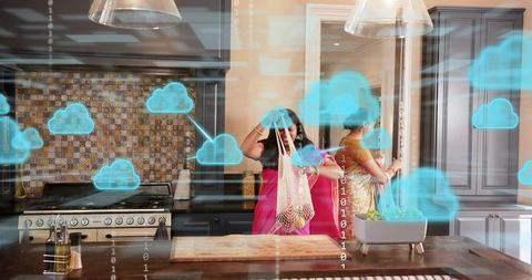 Indian women in sarees carrying mesh grocery bag in smart kitchen with cloud connectivity overlay