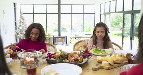 Diverse children sharing festive holiday meal at rustic wooden table with roasted chicken