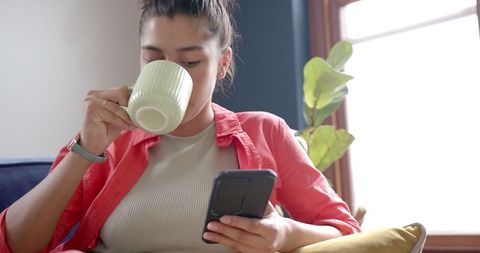 Teenage Girl Relaxing with Tea and Smartphone at Home