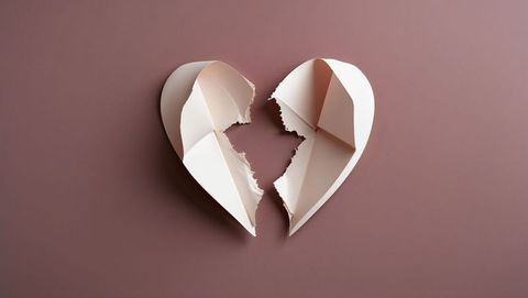 Torn paper heart on muted rose surface