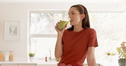Woman Enjoys Green Smoothie in Bright Minimalist Kitchen