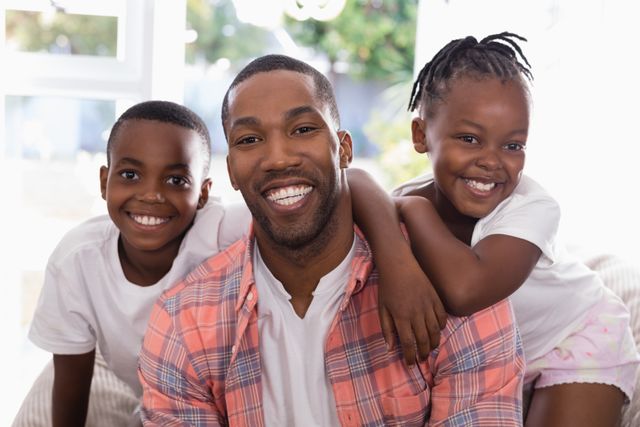 Portrait of cheerful father and children sitting on couch at home