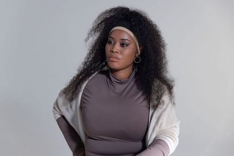 Poised african american woman posing in taupe top and cream cardigan, minimalist portrait