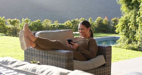 Woman Relaxing with Smartphone on Patio with Mountain View
