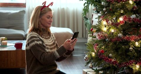 Mature Woman Celebrating Christmas at Home with Phone