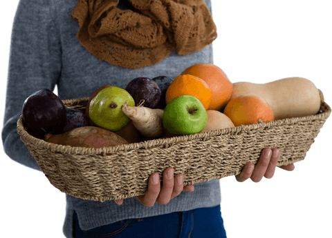 Woman holding basket of fresh fruits and vegetables on transparent background