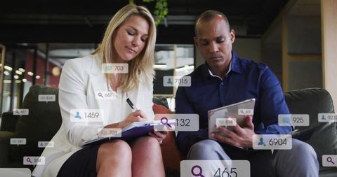 Collaborating professionals taking notes with tablet and paper notebook in modern coworking lounge
